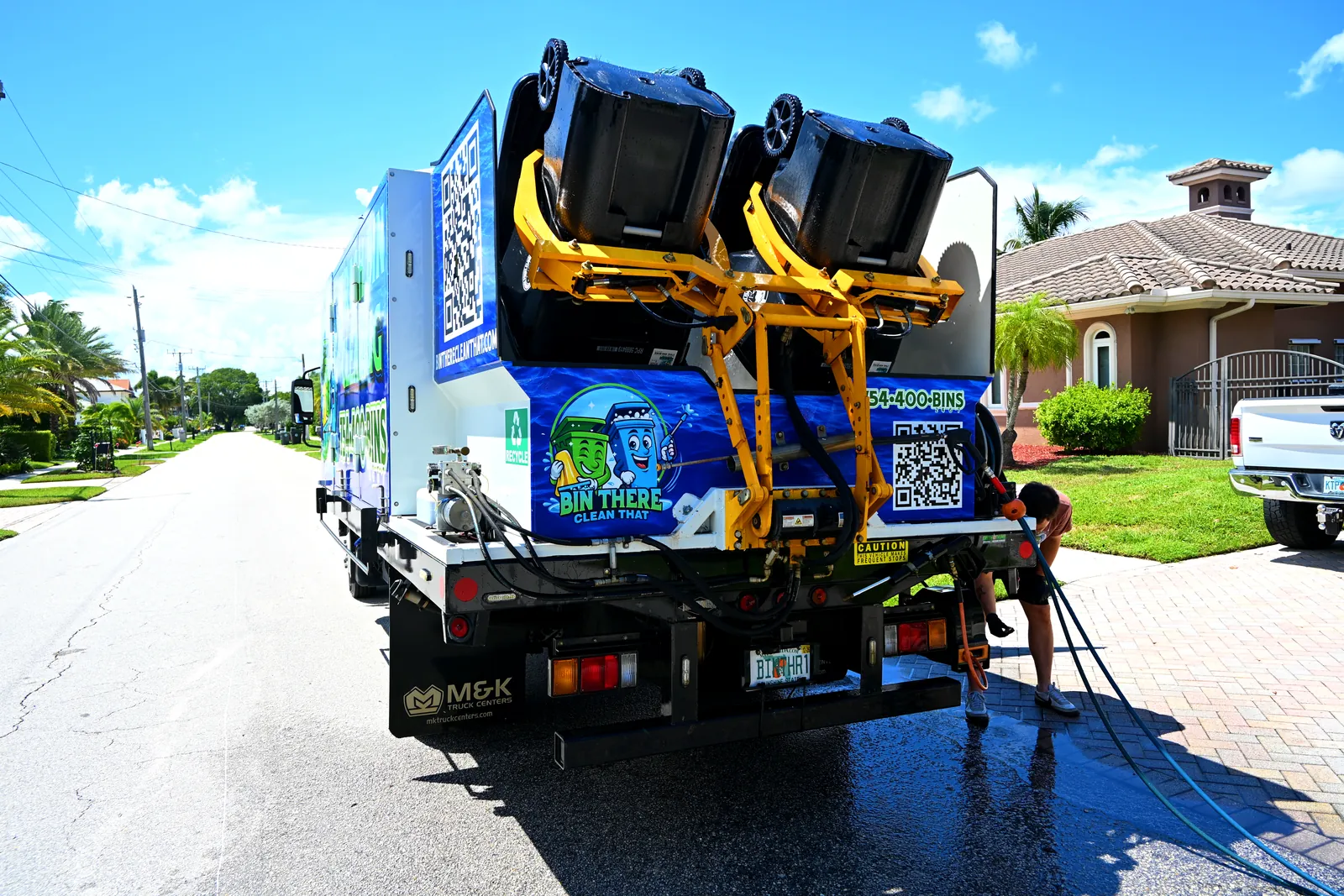 Bin There Clean That truck lifting two trash cans into its wash chamber on a South Florida street
