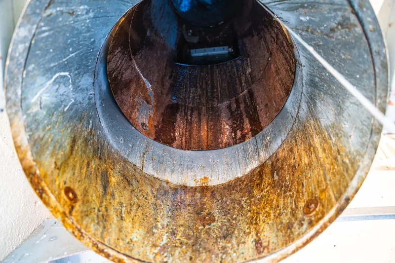 Trash chute before cleaning, coated in rust-colored buildup