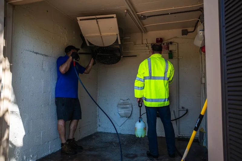 Two crew members cleaning a trash chute room