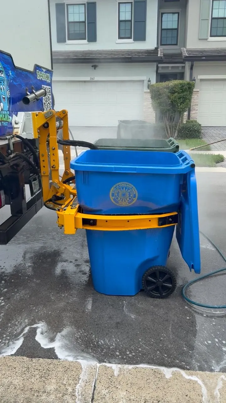 Blue bin on the lift beside a freshly rinsed driveway