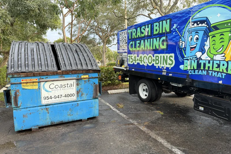 Freshly cleaned blue commercial dumpster with the Bin There Clean That truck behind it