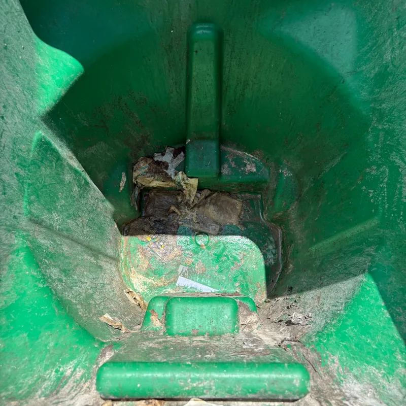 Green residential cart with trash and residue stuck to the bottom