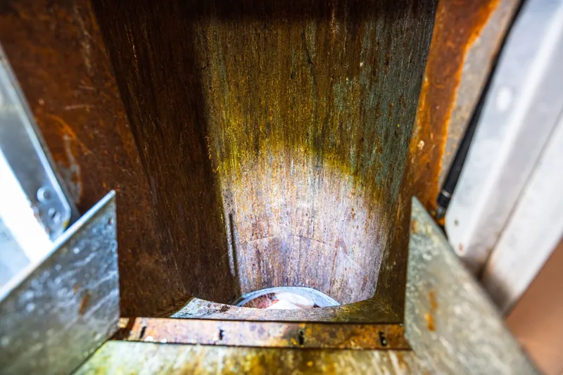 Bottom of a trash chute with rust and grime buildup